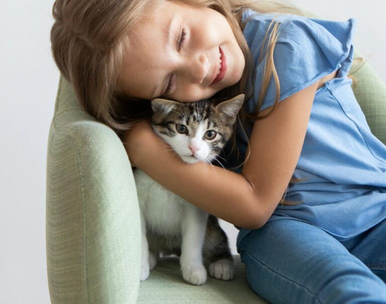 A happy child embracing a cute kitten while sitting on a chair indoors, showcasing warmth and love.